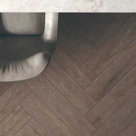Despacho de diseño visto desde arriba con suelo en espiga SPC Herringbone Moka de TRIP The Natural Company, mesa de mármol claro y sillón de piel.