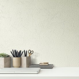 Zona de escritorio de diseño minimalista con pared revestida en SPC Ada Marfil de TRIP The Natural Company, organizadores de madera y plantas pequeñas.