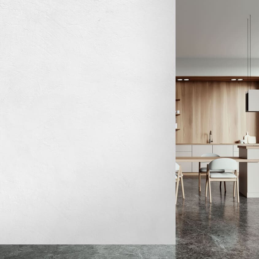 Pared de cocina moderna y diáfana revestida con SPC Skin Grey de TRIP The Natural Company, isla de cocina minimalista y armarios de madera.
